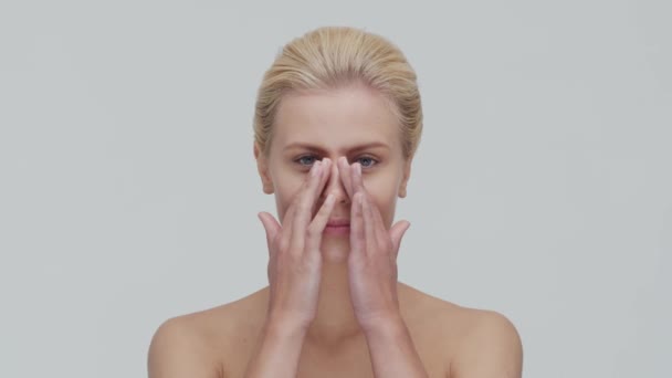 Studio portrait of young, beautiful and natural blond woman applying skin care cream. Face lifting, cosmetics and make-up. — Stock Video