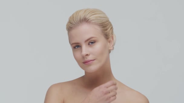 Studioporträt einer jungen, schönen und natürlichen blonden Frau, die Hautpflegecreme aufträgt. Gesichtslifting, Kosmetik und Make-up. — Stockvideo