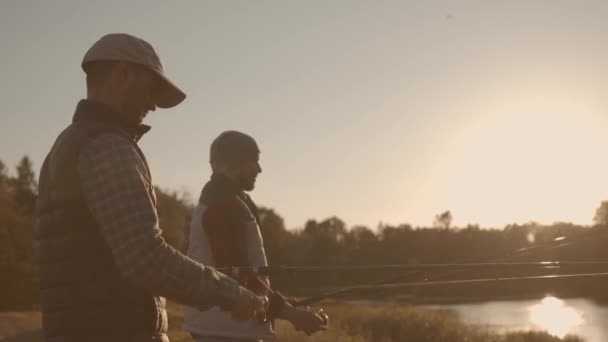 Fishermen friends with a spinning rod catching fish on a river. Fisher men on a weekend. Hobby, leisure and active summer and autumn concept. — ストック動画