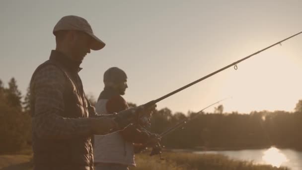 Fishermen friends with a spinning rod catching fish on a river. Fisher men on a weekend. Hobby, leisure and active summer and autumn concept. — ストック動画