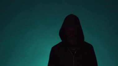 Kapüşonlu bilgisayar korsanı portresi. Karanlık bir yüz. Veri hırsızlığı, internet dolandırıcılığı, darknet ve siber güvenlik .