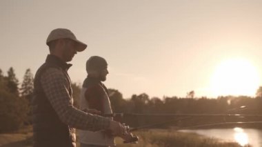 Nehirde balık tutan bir oltayla balıkçı arkadaşlar. Hafta sonu balık tutan adamlar. Hobi, boş zaman ve aktif yaz ve sonbahar konsepti.