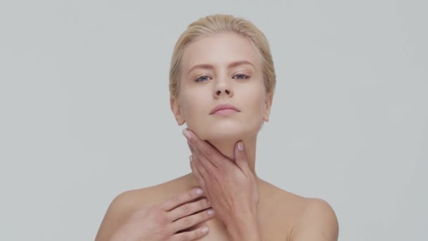 Studio portret van jonge, mooie en natuurlijke blonde vrouw die huidverzorgingscrème aanbrengt. Gezichtsheffen, cosmetica en make-up. — Stockvideo