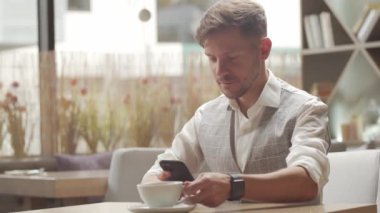 Bir kafede oturan ve çalışan bir iş adamı. Cep telefonu kullanan bir adam. İş ve Girişimcilik.