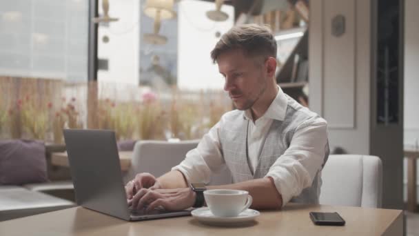 Zakenman zit en werkt in een café. Een man die computerapparatuur gebruikt. Bedrijfsleven en ondernemerschap. — Stockvideo