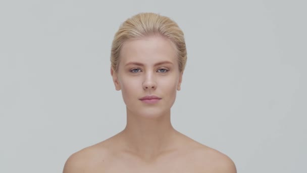 Studio portret van jonge, mooie en natuurlijke blonde vrouw die huidverzorgingscrème aanbrengt. Gezichtsheffen, cosmetica en make-up. — Stockvideo