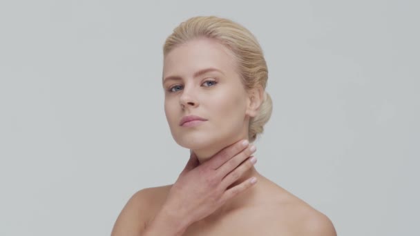 Studio portret van jonge, mooie en natuurlijke blonde vrouw die huidverzorgingscrème aanbrengt. Gezichtsheffen, cosmetica en make-up. — Stockvideo