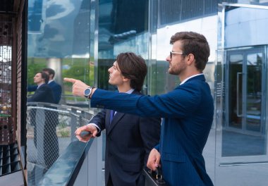 Kendine güvenen iş adamları modern ofis binasının önünde konuşuyorlar. İş adamı ve iş arkadaşı. Bankacılık ve finans piyasası.