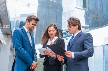 Modern ofis binasının önünde konuşan emin işadamlarının. İşadamlarının ve iş kadınının işi var. Bankacılık, profesyonel iş ve finansal piyasa konsepti.