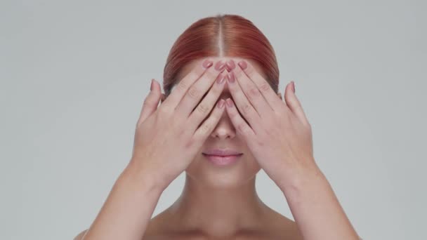 Portrait studio de jeune, belle et naturelle rousse femme appliquant crème de soin de la peau. lifting du visage, cosmétiques et maquillage . — Video