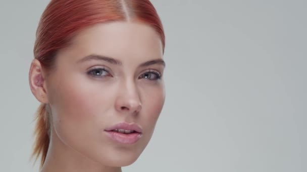 Retrato de estudio de mujer pelirroja joven, hermosa y natural aplicando crema para el cuidado de la piel. Levantamiento facial, cosméticos y maquillaje . — Vídeo de stock