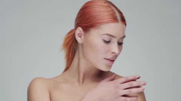 Studio portret van jonge, mooie en natuurlijke roodharige vrouw die huidverzorgingscrème aanbrengt. Gezichtsheffen, cosmetica en make-up. — Stockvideo