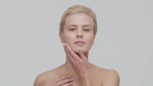 Studio porträtt av ung, vacker och naturlig blond kvinna som tillämpar hudvård grädde. Ansiktslyftning, kosmetika och make-up. — Stockvideo