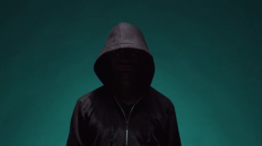 Kapüşonlu bilgisayar korsanı portresi. Karanlık bir yüz. Veri hırsızlığı, internet dolandırıcılığı, darknet ve siber güvenlik .
