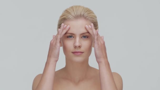 Studio portrait of young, beautiful and natural blond woman applying skin care cream. Face lifting, cosmetics and make-up. — Stock Video