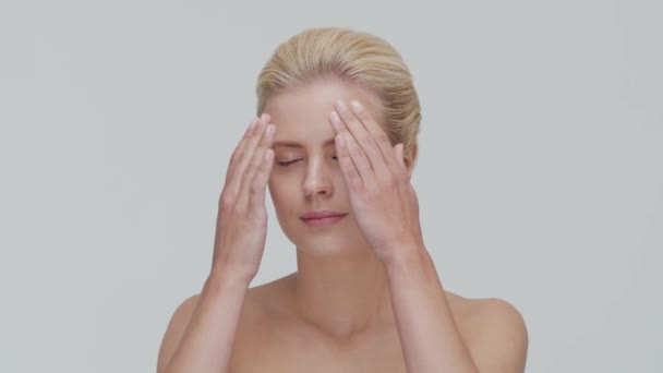 Studio portrét mladé, krásné a přírodní blond ženy, aplikující krém na péči o pleť. Zdvihání obličeje, kosmetika a make-up. — Stock video