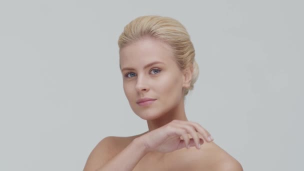 Studio portrét mladé, krásné a přírodní blond ženy, aplikující krém na péči o pleť. Zdvihání obličeje, kosmetika a make-up. — Stock video