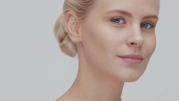 Studioporträt einer jungen, schönen und natürlichen blonden Frau, die Hautpflegecreme aufträgt. Gesichtslifting, Kosmetik und Make-up. — Stockvideo