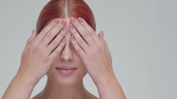 Studioporträt einer jungen, schönen und natürlichen rothaarigen Frau, die Hautpflegecreme aufträgt. Gesichtslifting, Kosmetik und Make-up. — Stockvideo