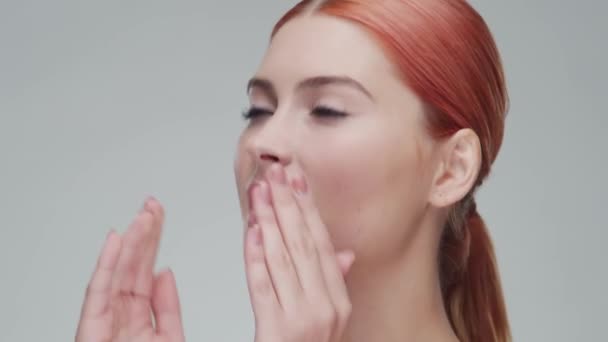 Studio portret van jonge, mooie en natuurlijke roodharige vrouw die huidverzorgingscrème aanbrengt. Gezichtsheffen, cosmetica en make-up. — Stockvideo