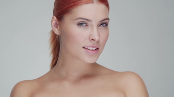 Portrait studio de jeune, belle et naturelle rousse femme appliquant crème de soin de la peau. lifting du visage, cosmétiques et maquillage . — Video