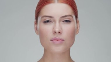 Cilt bakımı kremi süren genç, güzel ve doğal kızıl saçlı kadının stüdyo portresi. Yüz gerdirme, kozmetik ve makyaj konsepti.