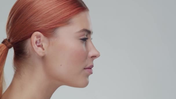 Studio porträtt av ung, vacker och naturlig rödhårig kvinna som tillämpar hudvård grädde. Ansiktslyftning, kosmetika och make-up. — Stockvideo