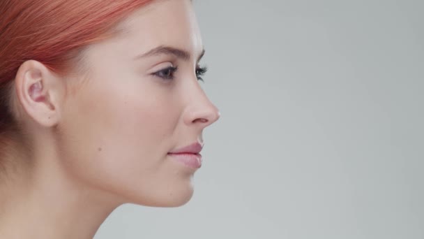 Retrato de estudio de mujer pelirroja joven, hermosa y natural aplicando crema para el cuidado de la piel. Levantamiento facial, cosméticos y maquillaje . — Vídeo de stock