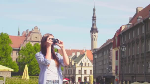 Attractive young girl traveling and exploring beautiful old town. Tourist with a retro camera. — Stock Video