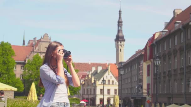 Attractive young girl traveling and exploring beautiful old town. Tourist with a retro camera. — Stock Video