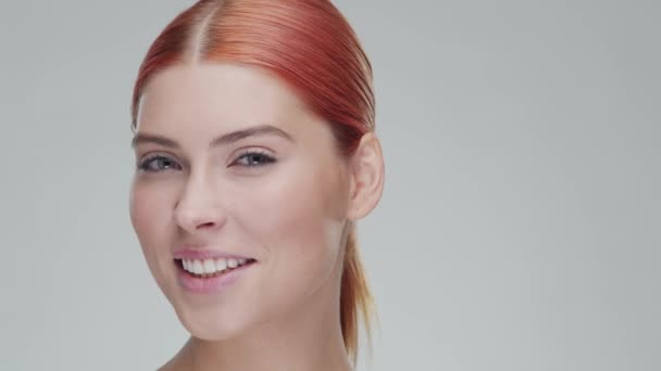 Studio portret van jonge, mooie en natuurlijke roodharige vrouw die huidverzorgingscrème aanbrengt. Gezichtsheffen, cosmetica en make-up. — Stockvideo