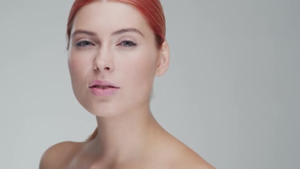 Studio πορτρέτο των νέων, όμορφη και φυσική κοκκινομάλλα γυναίκα εφαρμογή κρέμα φροντίδας του δέρματος. Ανόρθωση προσώπου, καλλυντικά και μακιγιάζ. — Αρχείο Βίντεο