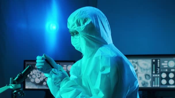 穿着防护服的科学家和使用实验室设备在研究实验室工作的面罩 显微镜 Coronavirus 2019 Ncov Hazard Pharmaceutical Discovery Bacterology Virology — 图库视频影像