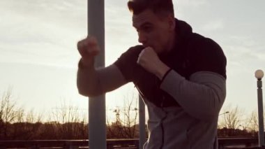 Genç ve zinde bir adam dışarıda akşam antrenmanı yapıyor. Şehir günbatımı geçmişi. Spor ve spor kavramları.