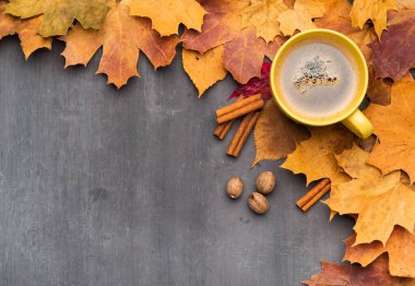 Mevsimlik sonbahar geçmişi. Renkli akçaağaç yaprakları ve bir fincan sıcak içecek, kahve, latte veya kapuçino, hindistan cevizi ve tarçın..