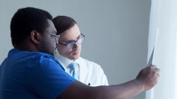 医生和外科医生站在窗边看着X光 医院的医务工作者 天亮了保健 团队精神概念 — 图库视频影像