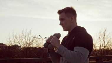 Genç ve zinde bir adam dışarıda akşam antrenmanı yapıyor. Şehir günbatımı geçmişi. Spor ve spor kavramları.