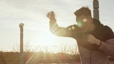 Genç ve zinde bir adam dışarıda akşam antrenmanı yapıyor. Şehir günbatımı geçmişi. Spor ve spor kavramları.