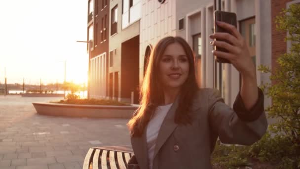 Genç Çekici Bir Kadını Bankta Oturup Selfie Çekiyor Gün Batımı — Stok video