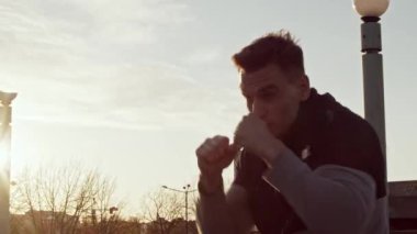 Genç ve zinde bir adam dışarıda akşam antrenmanı yapıyor. Şehir günbatımı geçmişi. Spor ve spor kavramları.