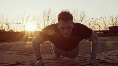 Genç ve zinde bir adam dışarıda akşam antrenmanı yapıyor. Şehir günbatımı geçmişi. Spor ve spor kavramları.