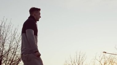 Genç ve zinde bir adam dışarıda akşam antrenmanı yapıyor. Şehir günbatımı geçmişi. Spor ve spor kavramları.