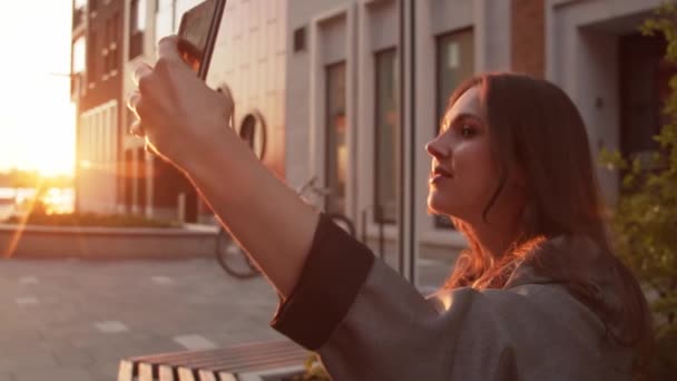 Genç Çekici Bir Kadını Bankta Oturup Selfie Çekiyor Gün Batımı — Stok video