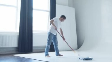 Paten boyacısı ve beyaz boya kullanarak fotoğraf stüdyosunda siklonama çizen genç bir adam.