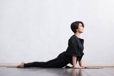 Sınıfta yoga yapan genç ve formda bir kadın. Gün ışığında esneme egzersizi. Spor, spor, sağlık hizmetleri ve yaşam tarzı kavramları.