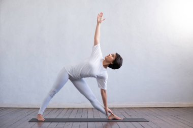 Sınıfta yoga yapan genç ve formda bir kadın. Gün ışığında esneme egzersizi. Spor, spor, sağlık hizmetleri ve yaşam tarzı kavramları.