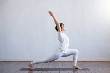 Sınıfta yoga yapan genç ve formda bir kadın. Gün ışığında esneme egzersizi. Spor, spor, sağlık hizmetleri ve yaşam tarzı kavramları.
