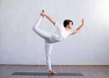 Sınıfta yoga yapan genç ve formda bir kadın. Gün ışığında esneme egzersizi. Spor, spor, sağlık hizmetleri ve yaşam tarzı kavramları.