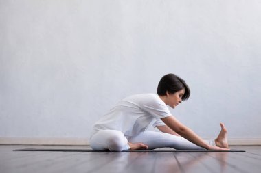 Sınıfta yoga yapan genç ve formda bir kadın. Gün ışığında esneme egzersizi. Spor, spor, sağlık hizmetleri ve yaşam tarzı kavramları.