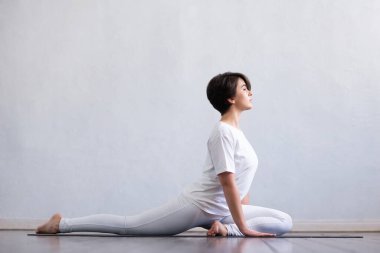 Sınıfta yoga yapan genç ve formda bir kadın. Gün ışığında esneme egzersizi. Spor, spor, sağlık hizmetleri ve yaşam tarzı kavramları.